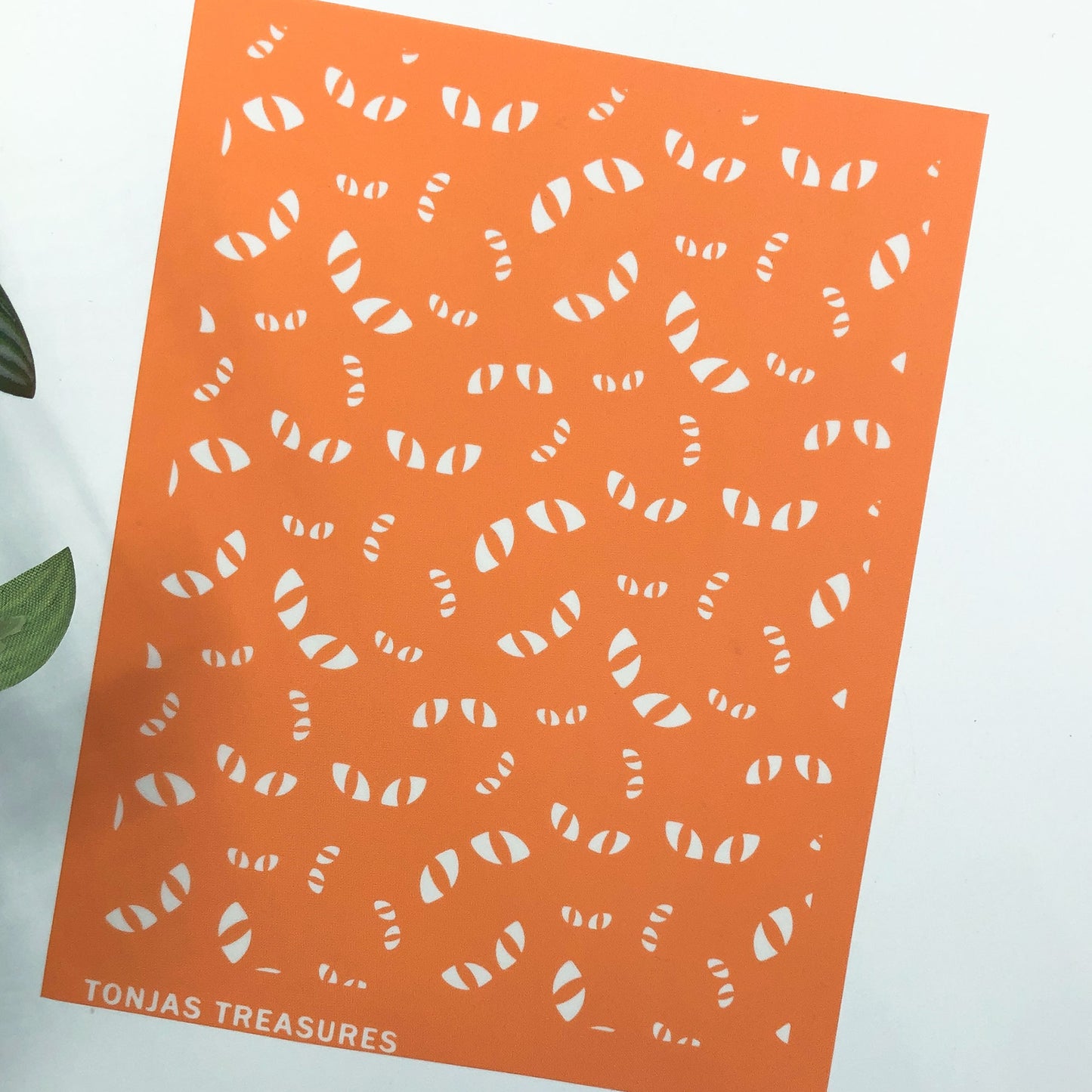 An orange rectangular silkscreen stencil on a white background with a small green leaf at the left edge. The text 'TONIAS TREASURES' appears in white at the bottom left.