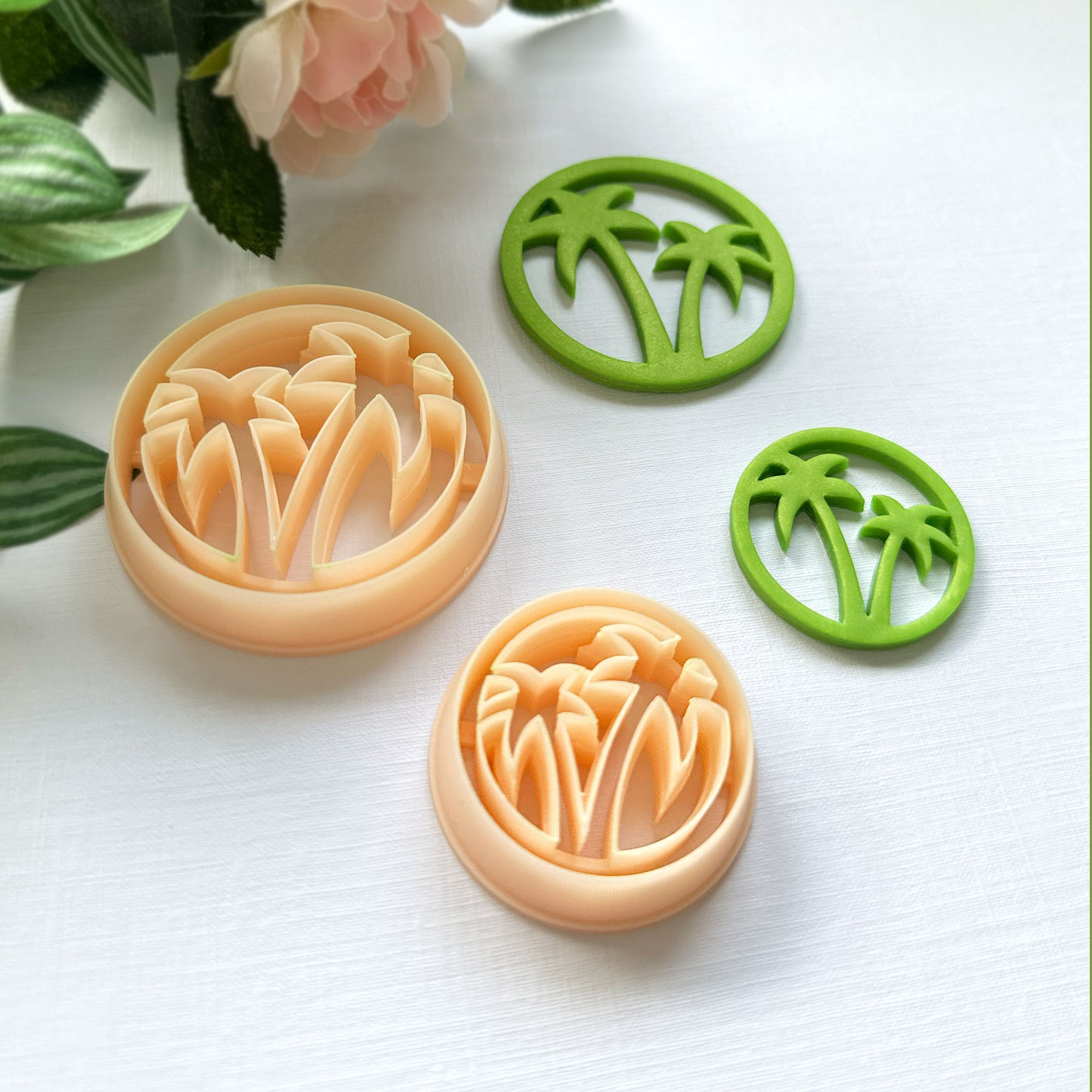 Set of clay cutters with floral and palm tree designs on a white surface.