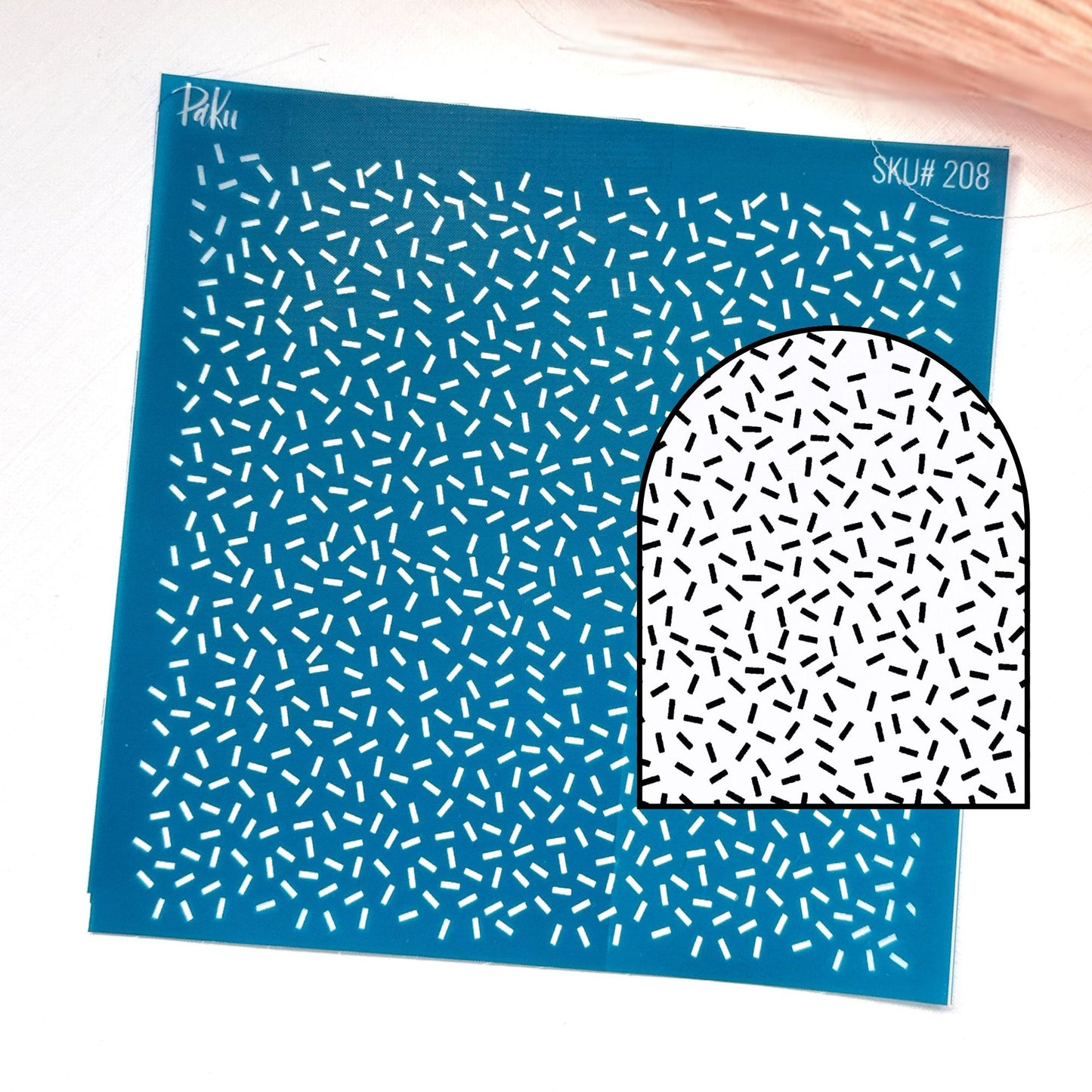 A blue patterned silkscreen stencil with small white dash-like marks, shown on a white background with a smaller inset of a white arch-shaped area covered in black dash-like marks. Visible text includes 'Paku' and 'SKU# 208'.