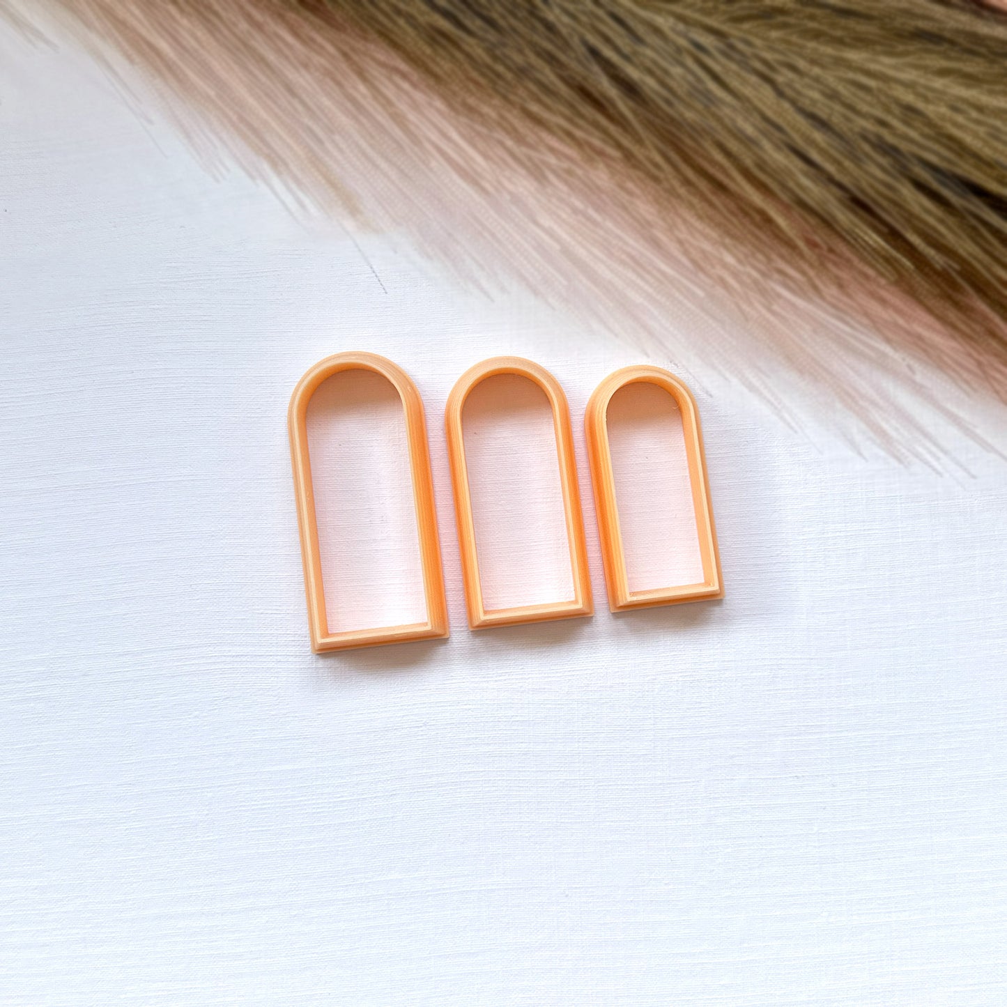 Three slim arch clay cutters on a white surface with a blurred background