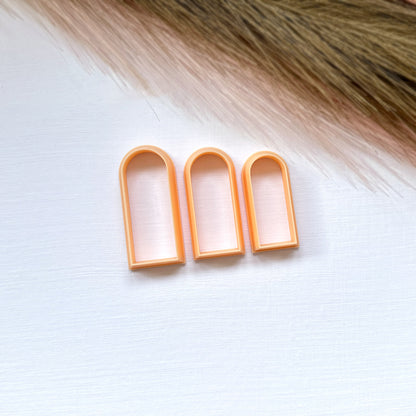 Three slim arch clay cutters on a white surface with a blurred background