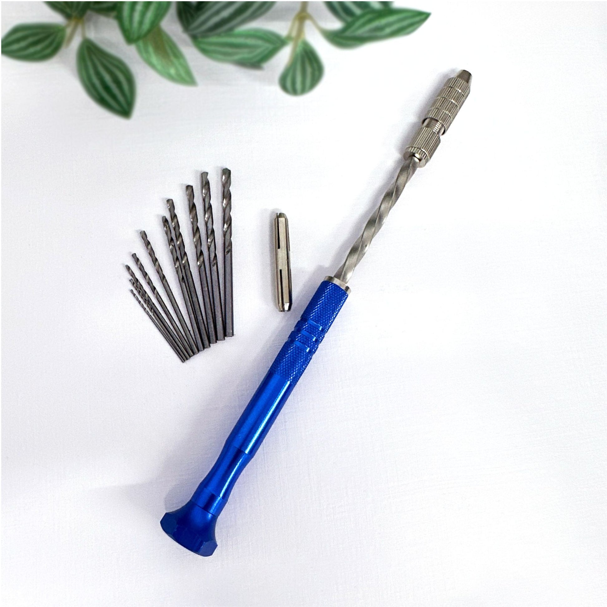 Blue semi-automatic push hand drill with drill bits for crafts on a white surface