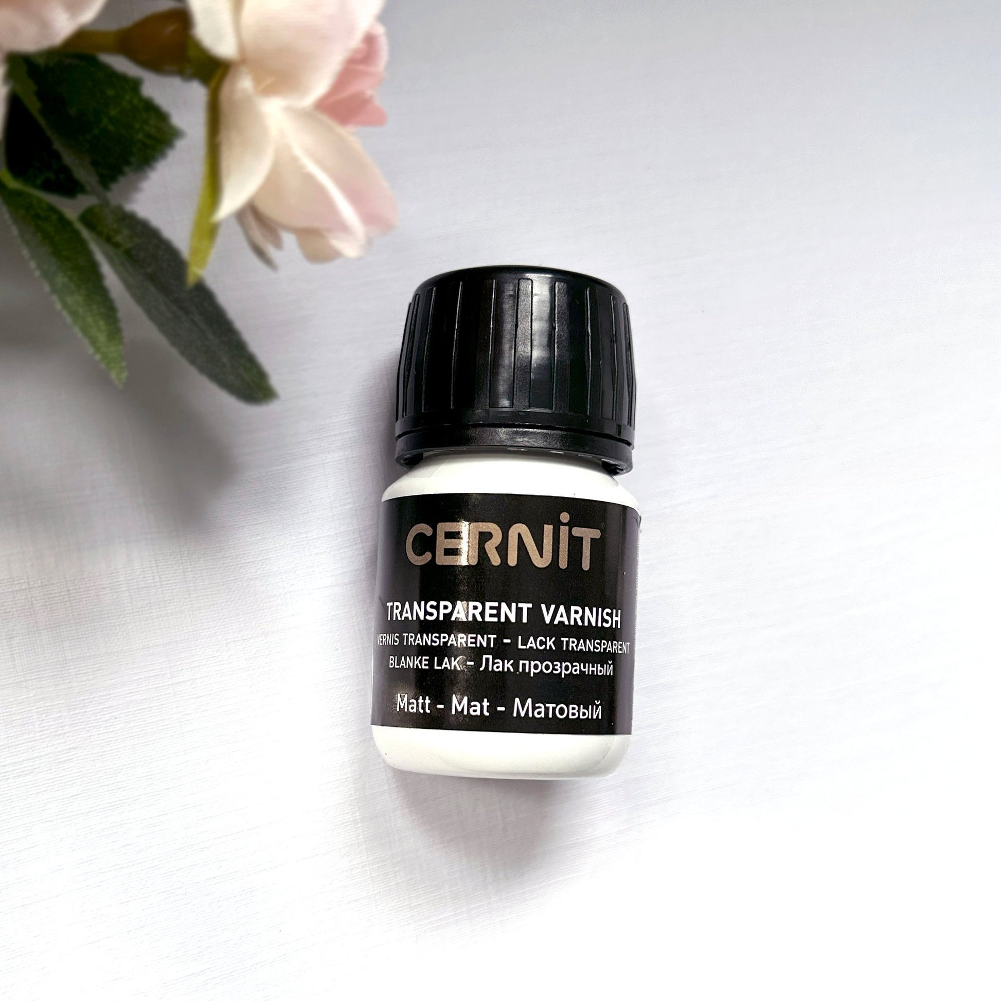 Cernit transparent varnish bottle on a light background with flowers - matt