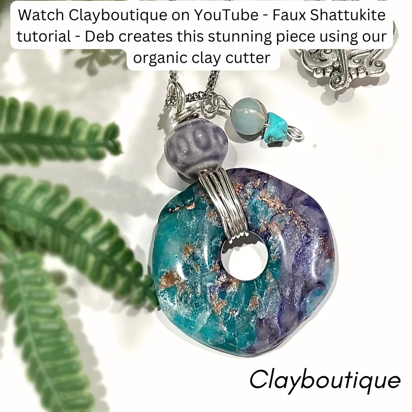 A handmade pendant necklace featuring a marbled turquoise and purple clay disc with gold flecks, accented by a purple bead and a small turquoise charm, shown with decorative green leaves on a white background with text overlays.