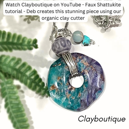 A handmade pendant necklace featuring a marbled turquoise and purple clay disc with gold flecks, accented by a purple bead and a small turquoise charm, shown with decorative green leaves on a white background with text overlays.