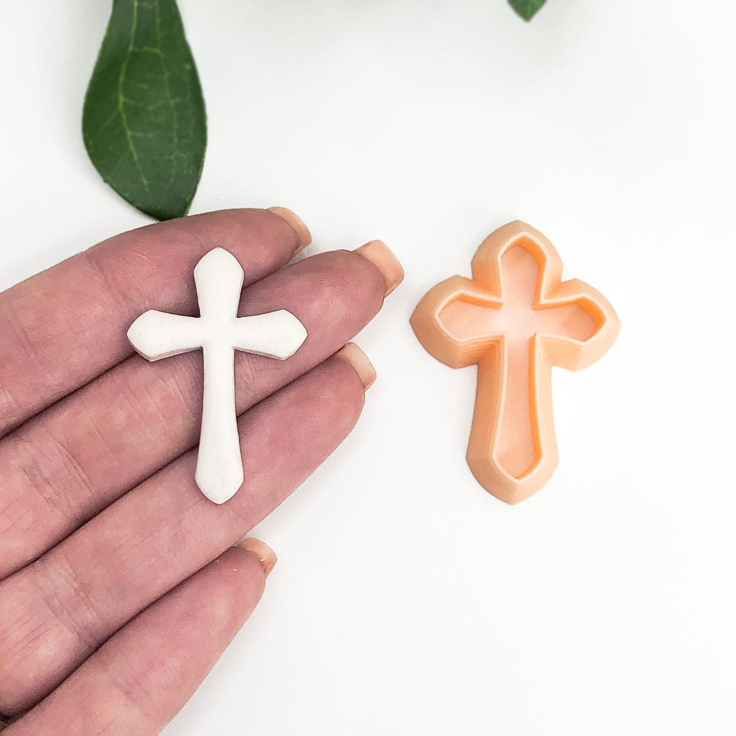 Cross clay cutter with the polymer clay cut out on a hand on a white background