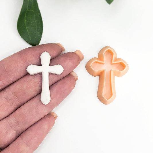 Cross clay cutter with the polymer clay cut out on a hand on a white background