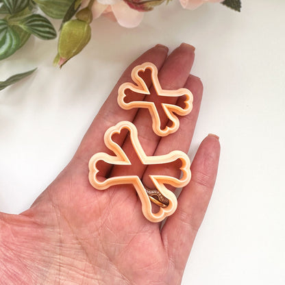 A peach plastic cookie clay cutter in the shape of crossed bones.