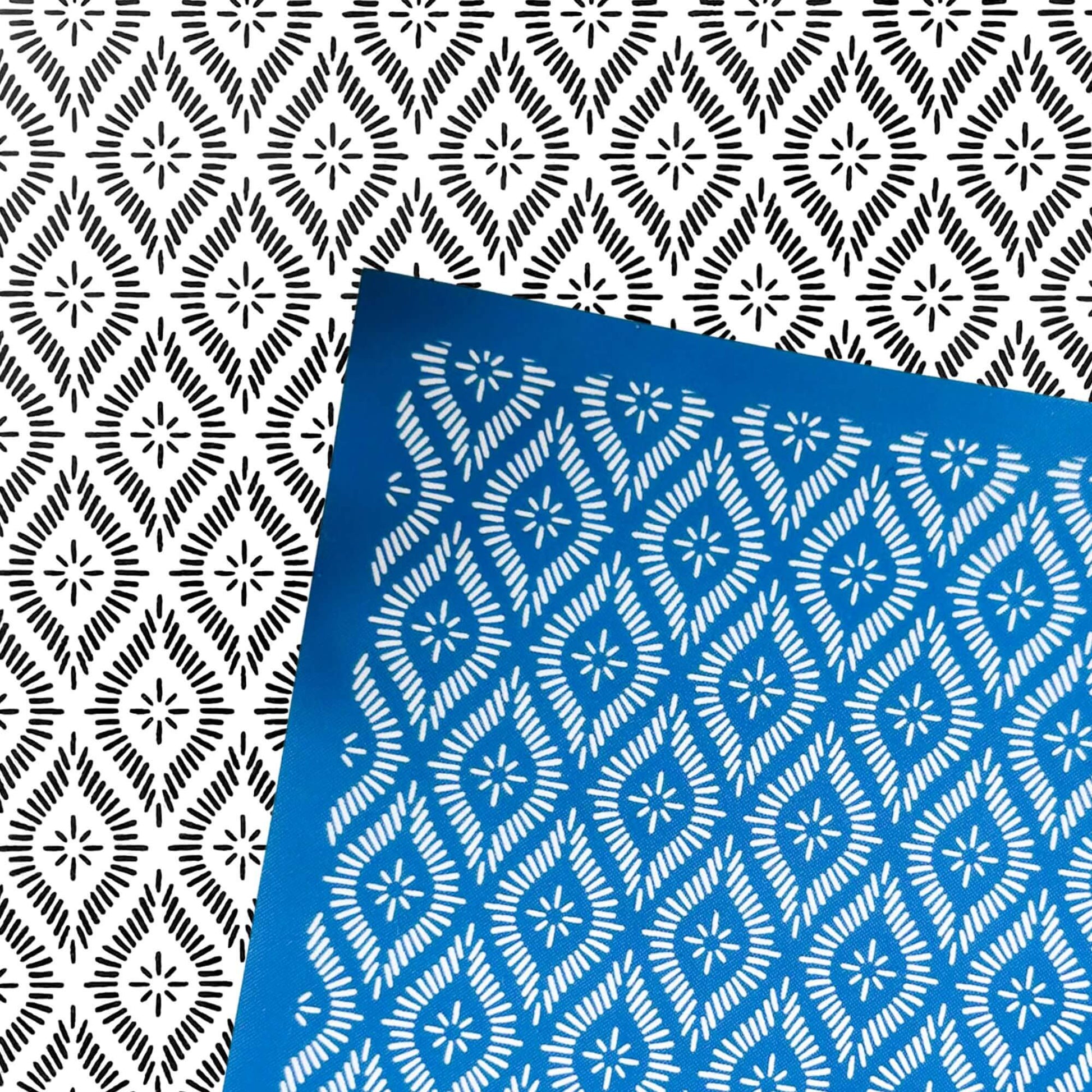 A blue rectangular silkscreen stencil with a white repeating geometric star-and-diamond pattern, placed diagonally over a black-and-white patterned background. 