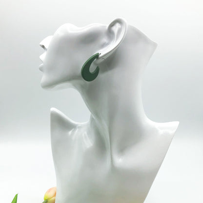 A dark green crescent-shaped hoop earring displayed on a white ceramic female bust against a light gray background.