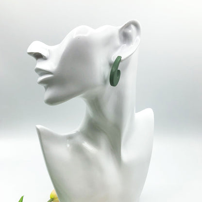A dark green curved hoop earring displayed on a white ceramic female bust against a light gray background.
