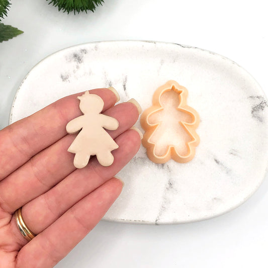 Gingerbread girl clay cutter - polymer clay cut out on a  hand with the peach clay cutter sat on a marble white tray