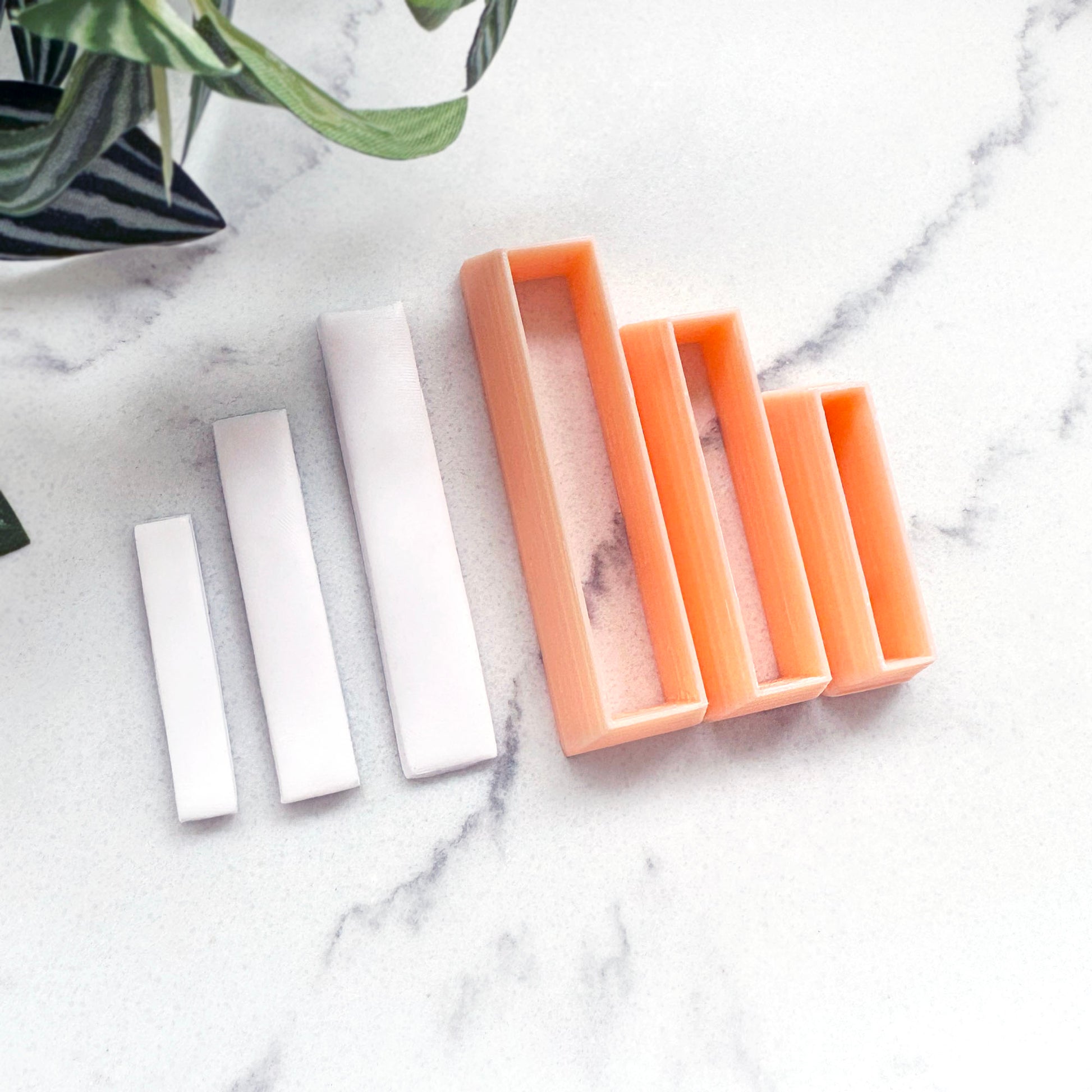 small white rectangular Polymer clay bar, with a peach-colored rectangular clay cutter beside it on a white surface.
