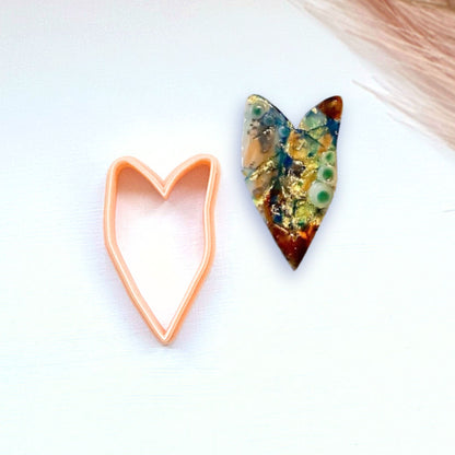 Heart-shaped clay cutter next to a heart-shaped polymer clay piece on a white background - organic cookie cutter