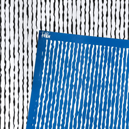 A blue square silkscreen stencil with vertical wavy organic lines, placed diagonally over a black and white striped patterned background. The brand name 'Paku' is visible in white script on the top-left corner of the blue sheet.