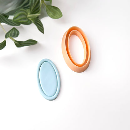A light blue oval-shaped polymer clay cut out with a framed edge. A  peach-coloured oval-shaped clay cutter is also shown.