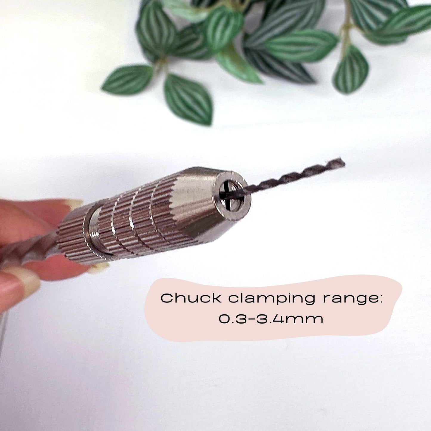 Drill bit held by a hand with text indicating chuck clamping range on a white background with green leaves.