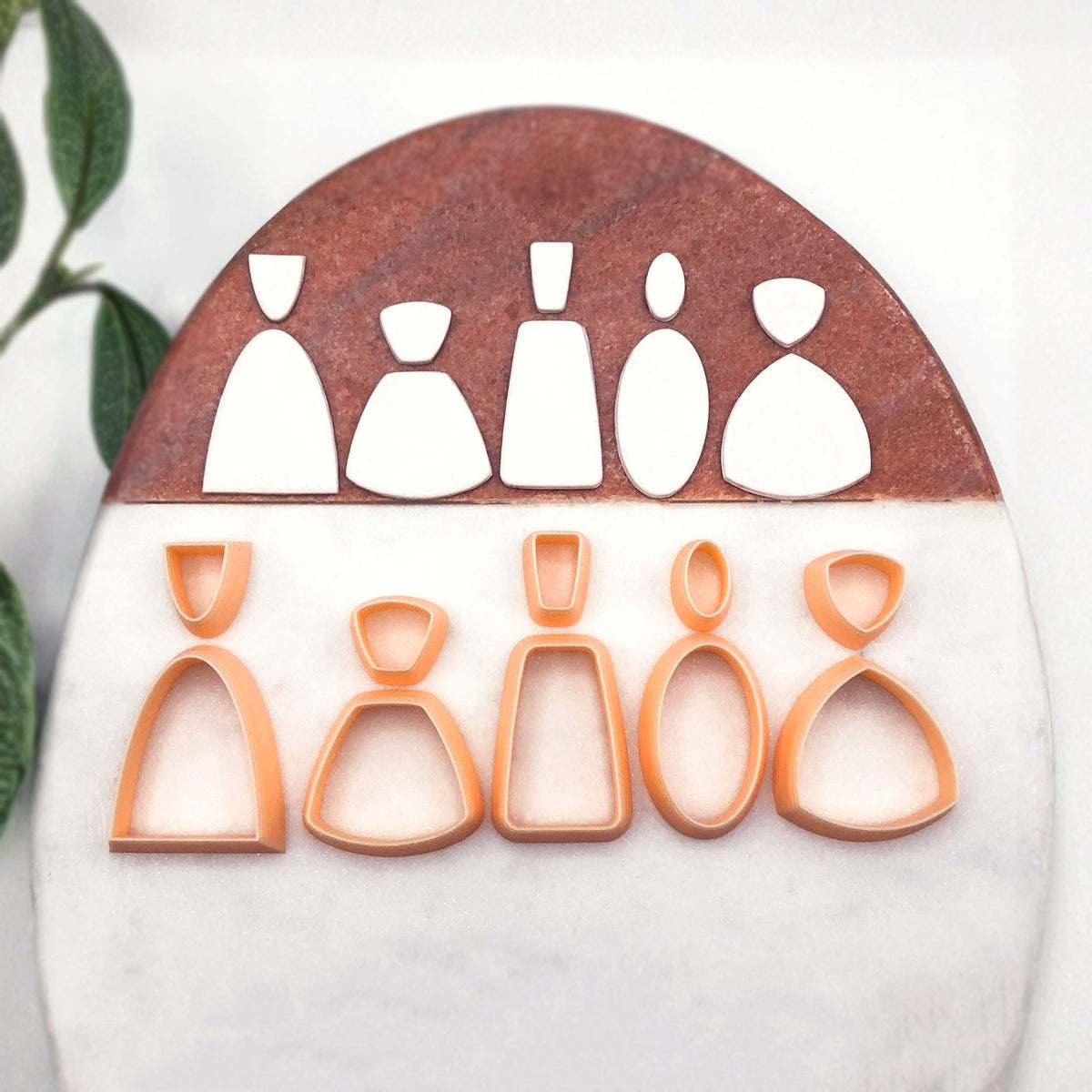 A starter set of 10 peach cookie clay cutters in different silhouette shapes, displayed on a split white and brown stone background.