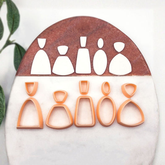 A starter set of 10 peach cookie clay cutters in different silhouette shapes, displayed on a split white and brown stone background.