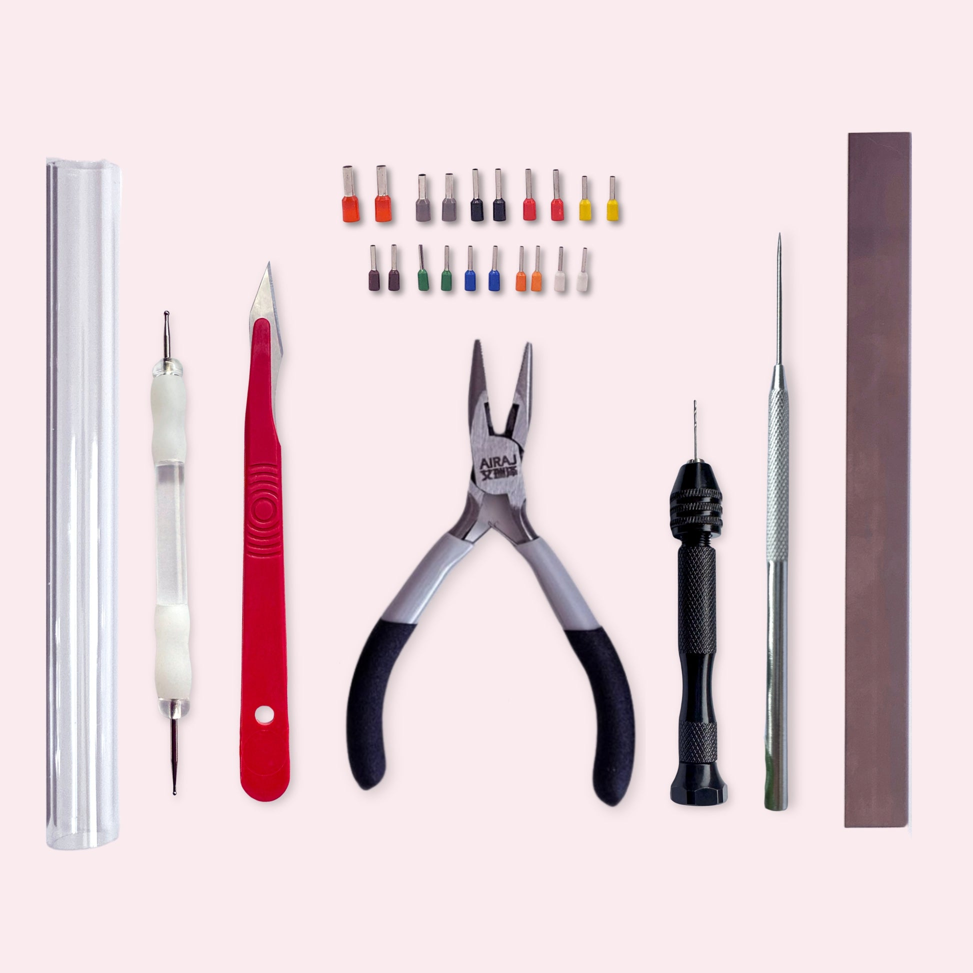 Set of tools including pliers, ball tools, and other precision instruments on a light pink background
