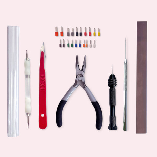 Set of tools including pliers, ball tools, and other precision instruments on a light pink background