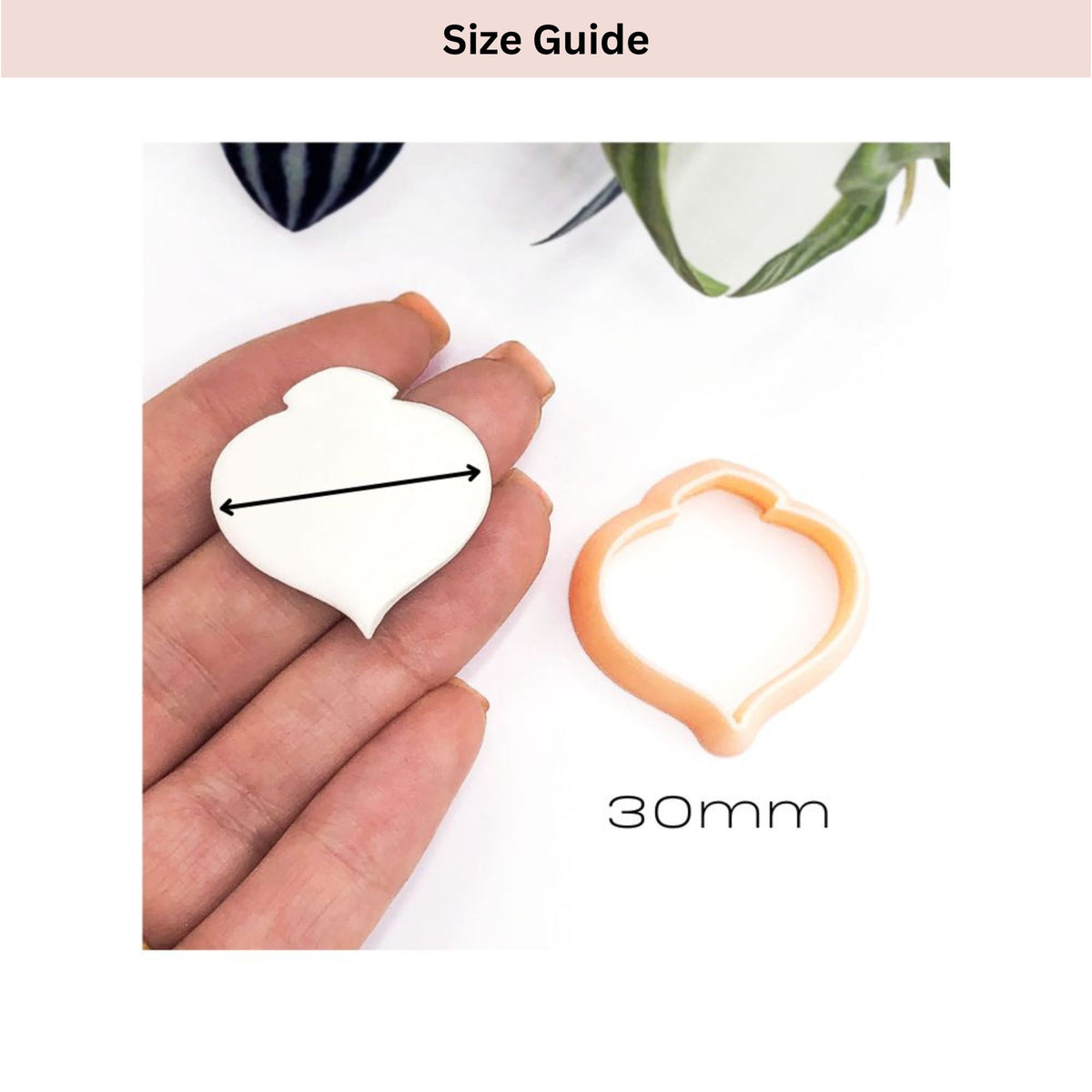 Size guide showing a 30mm bauble-shaped cookie cutter next to a hand holding a matching heart-shaped dough piece with a dimension arrow labeled 30mm.