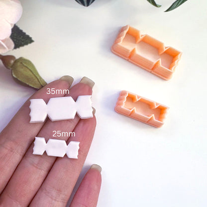 A hand holds two small white sweet-shaped pieces next to two peach-colored plastic cookie cutters, with size labels '35mm' and '25mm' overlaid on the image.