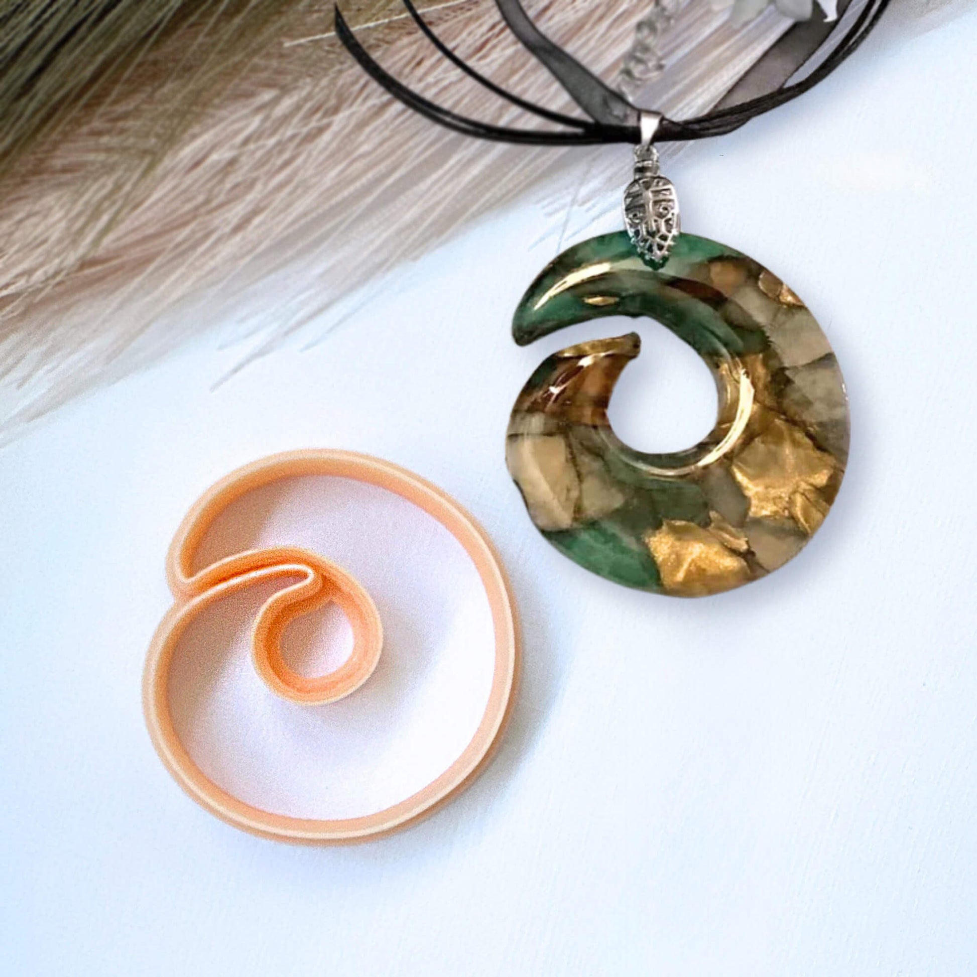 Decorative spiral ring pendant on a white surface and the Clay Cutter for polymer clay