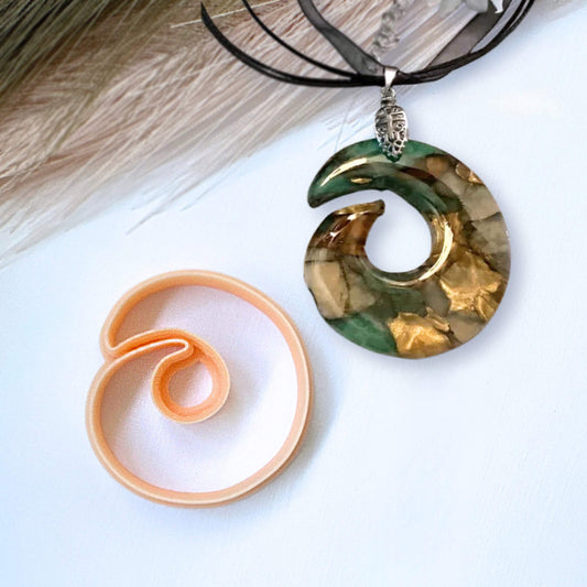 Decorative spiral ring pendant on a white surface and the Clay Cutter for polymer clay