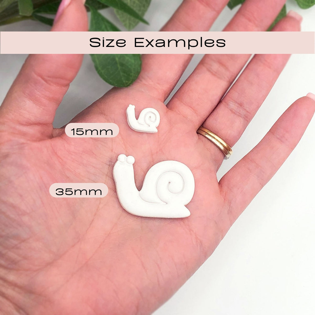 Snail Clay Cutter | Embossed - hand holding white snail shaped polymer clay cut out in a 15mm and 35mm