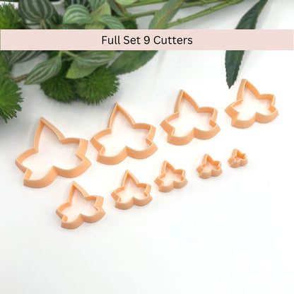 Set of Nine pale peach ivy leaf-shaped cookie clay cutters on a white marble surface 