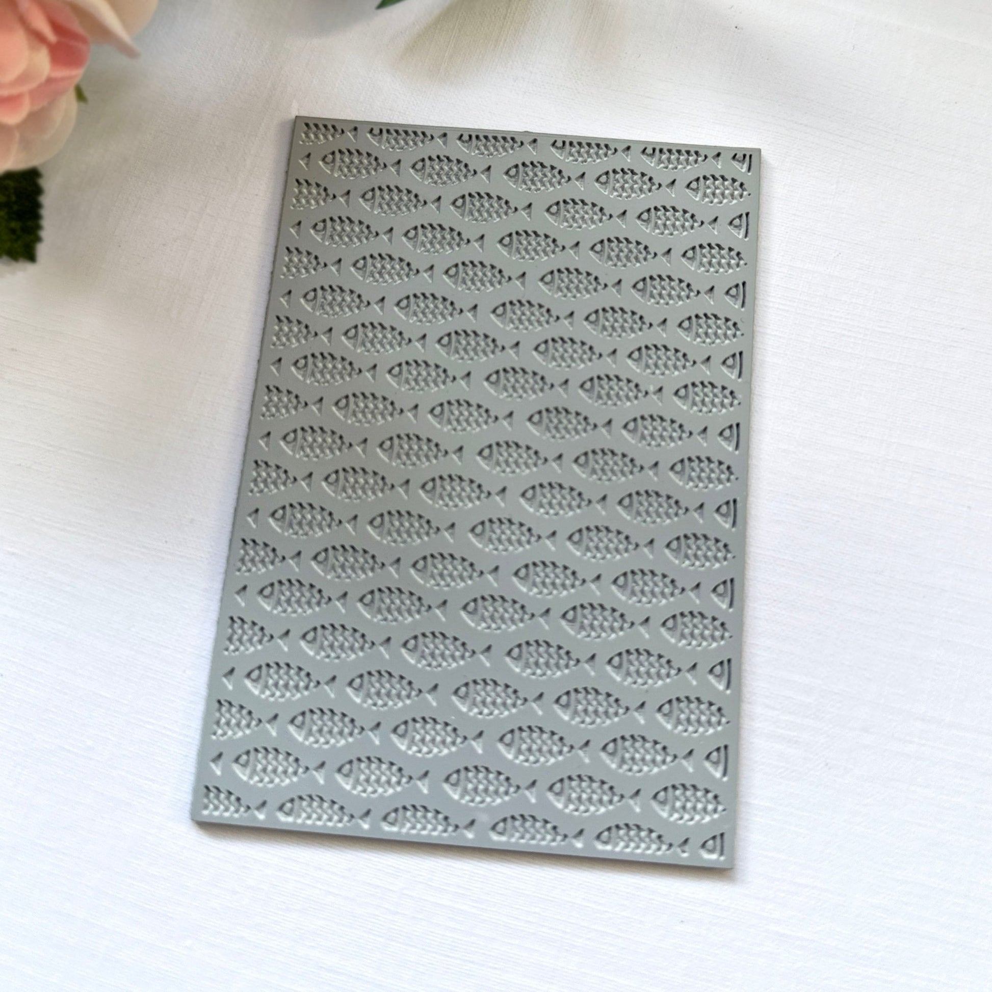 A texture stamp with a school-of-fish print against a light background with flowers.