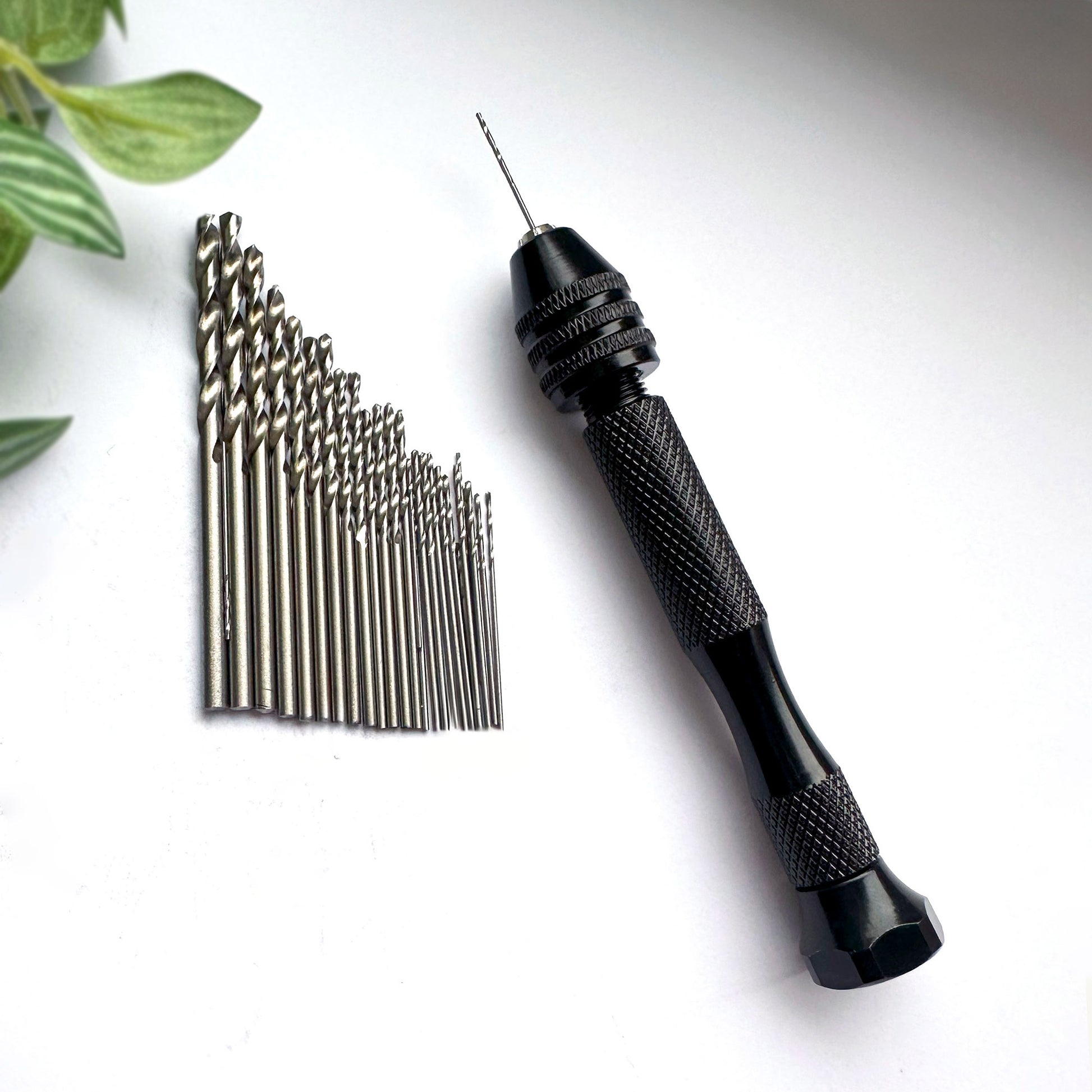Black drill bit set with a hand drill on a white background