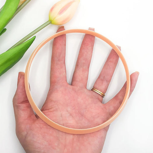 Large circle clay cutter for pottery, polymer and airdry clay. The circle is being held in a hand with flowers on a white background.