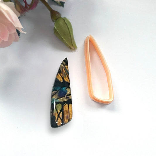 Clayboutique organic scalene dagger peach clay cutter shown next to a finished polymer clay cut out bead of the shape.