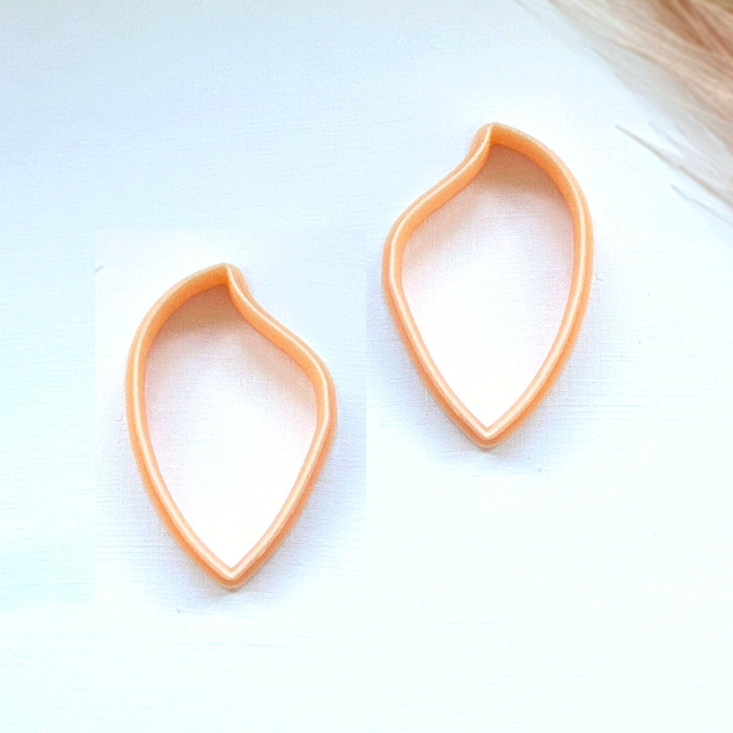 Two peach-colored teardrop-shaped stud earrings on a white background.