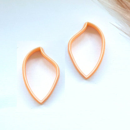 Two peach-colored teardrop-shaped stud earrings on a white background.