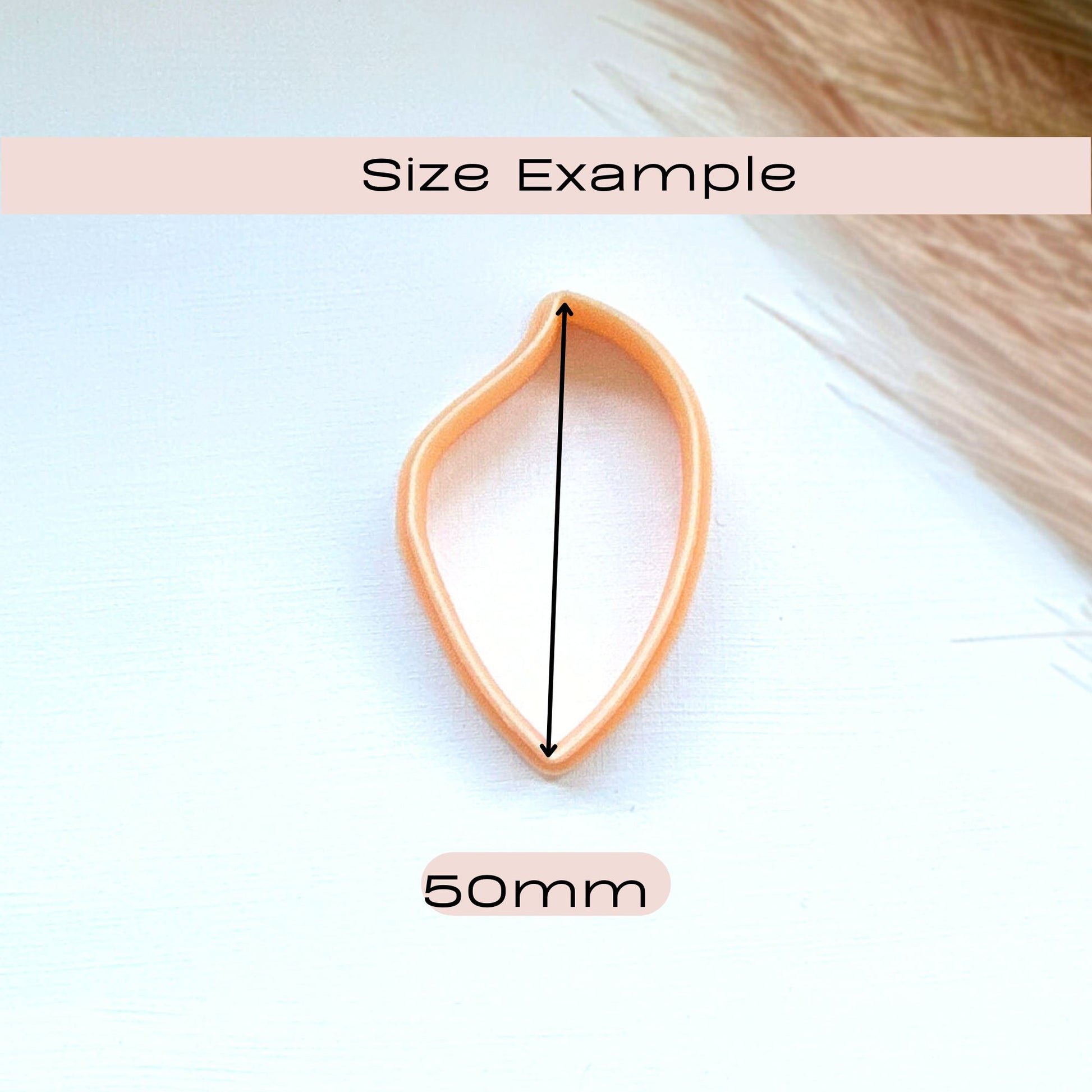 A peach-colored teardrop-shaped hair clip or hair pin shown on a white background with a black vertical measurement arrow and text labels reading 'Size Example' and '50mm' to indicate scale.