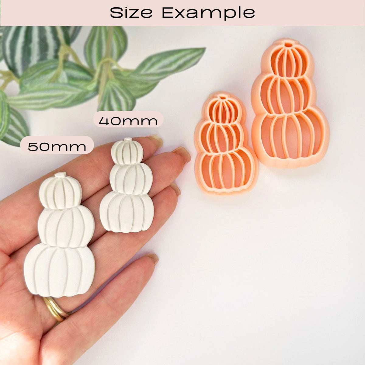 Size example image showing two small pumpkin-shaped clay cut outs in a hand, labelled 50 mm and 40mm, alongside two peach-colored pumpkin-shaped clay cutters on a white background with a leafy prop.