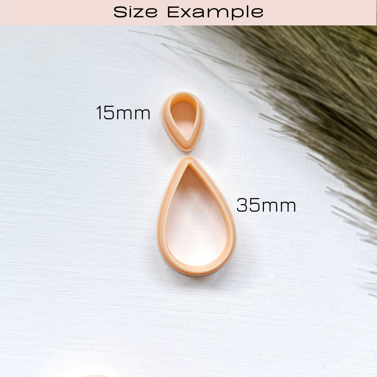 Size example of 2 peach-coloured plastic clay cutters in sizes   15mm and 35mm. The cutters are shaped like raindrops