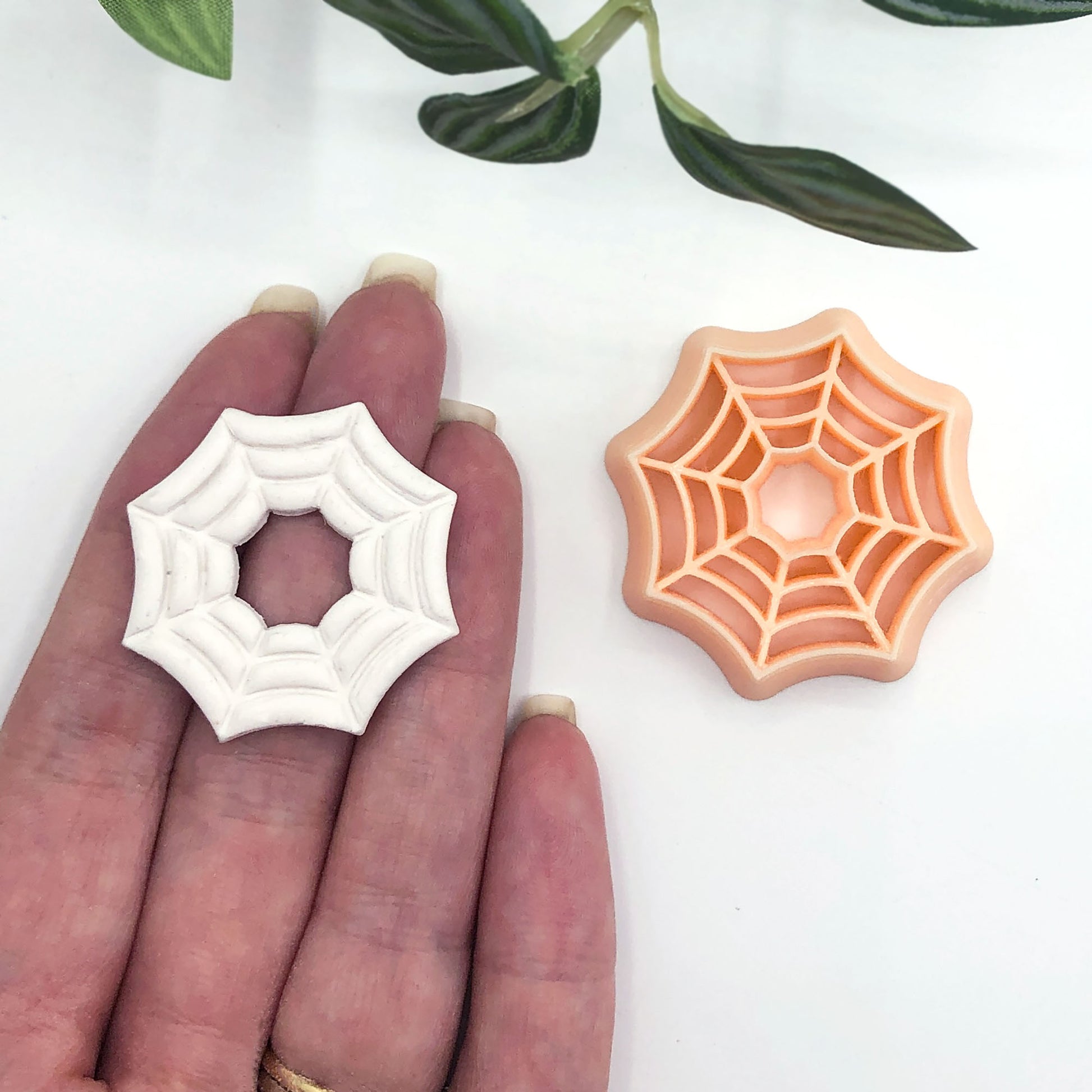 spider web clay cutters in a 35mm and polymer clay spiderweb cut out made using the cutters on a hand