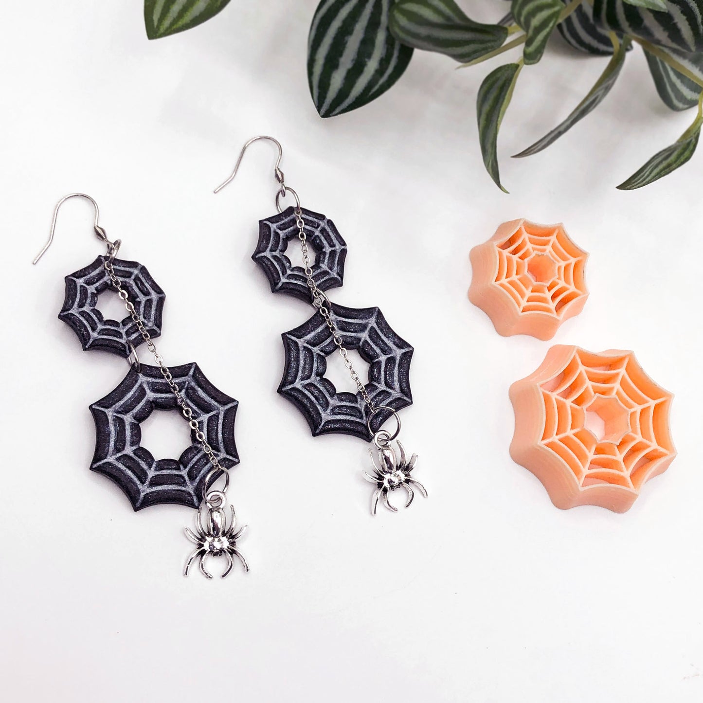 Spider web earrings with spider charms on a white background. spider web clay cutters in a 25 and 35mm, and polymer clay spiderweb earrings made using the cutters