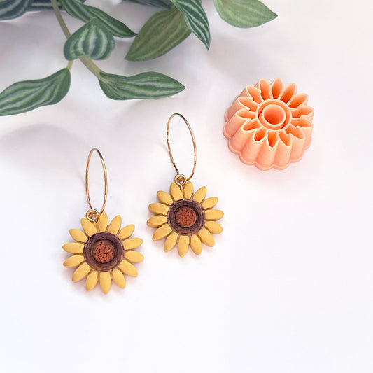 Sunflower-shaped polymer clay earrings with a sunflower clay cutter on a white background