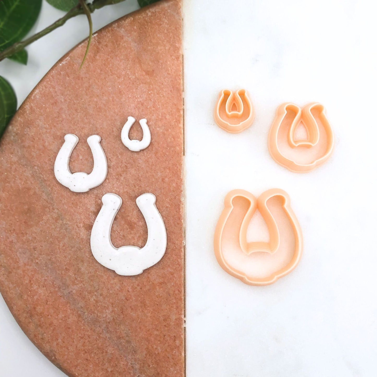Three horseshoe-shaped cookie cutters in peach and three matching white horseshoe cutouts on a split brown-and-white background.